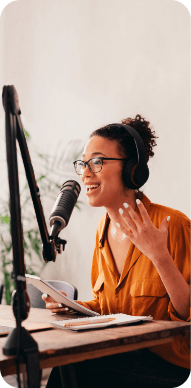 Jornalista com carderno em uma das mãos, gesticulando com a outra enquanto grava um podcast