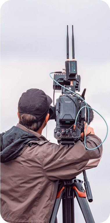 Homem de costas segurando uma filmadora profissional presa a um tripé
