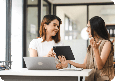 Três pequenos vasos brancos com plantas sobre uma mesa que também tem um celular e um caderno aberto com caneta sobre ele