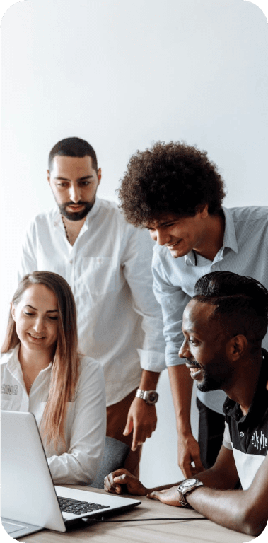 Grupo de três homens e uma mulher discutindo algo de forma descontraída em frente a tela de um computador