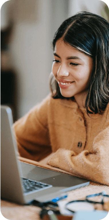 Garota sentada sorrindo em frente a um computador