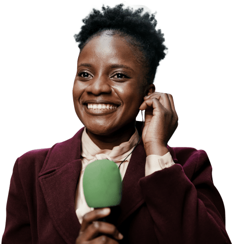 Repórter sorrindo, segurando um microfone verde com a mão direita e ajustando o ponto de escuta em sua orelha com a mão esquerda